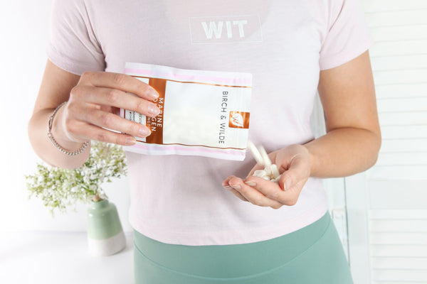 A woman wearing a white t-shirt and green trousers pours Birch & Wilde marine collagen capsules from a refill pouch into her open cupped hand