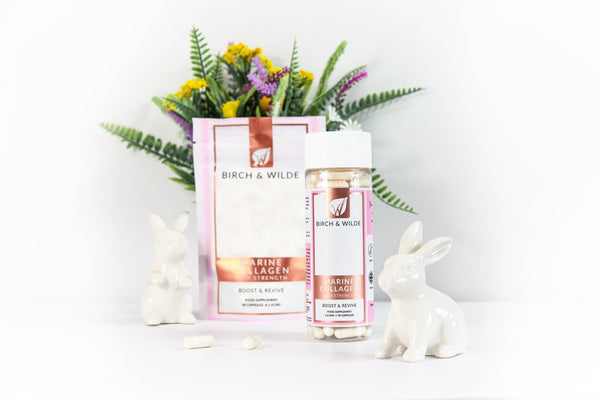 Image of a birch and wilde marine collagen refill pouch with a bottle of birch and wilde marine collagen capsules with a small white ceramic rabbit to one side and a healthy green houseplant with small yellow flowers in the background