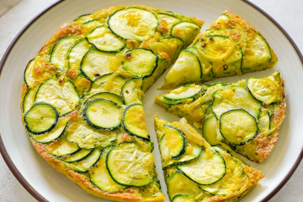 courgette zucchini frittata with fresh eggs and seasonal courgettes cut into slices and on a white plate