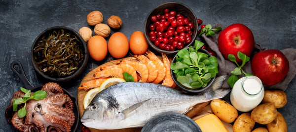 image of a selection of iodine rich foods taken from above against a dark grey background, including fish, prawns, seaweed and eggs