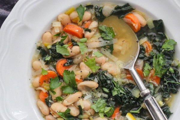 Image of Leek, Cannellini Bean & Lemon Kale Soup taken from above with the colourful soup served in a white ceramic bowl