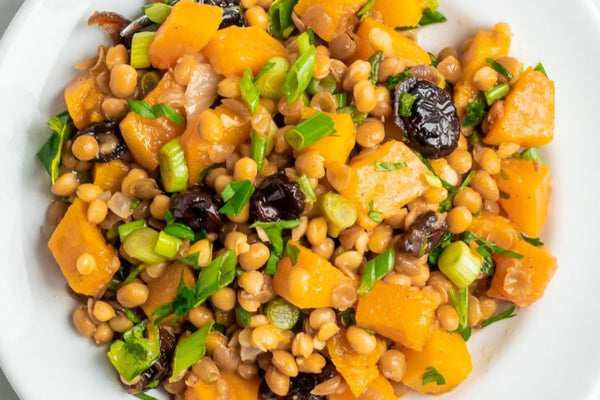 Image of a white ceramic bowl filled with warm maple roasted butternut squash and lentil salad, taken from above