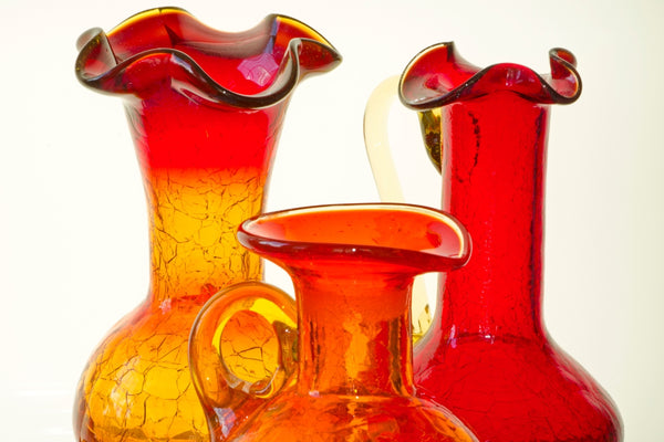 Image of the upper portions and necks of three red glass vases against a white background