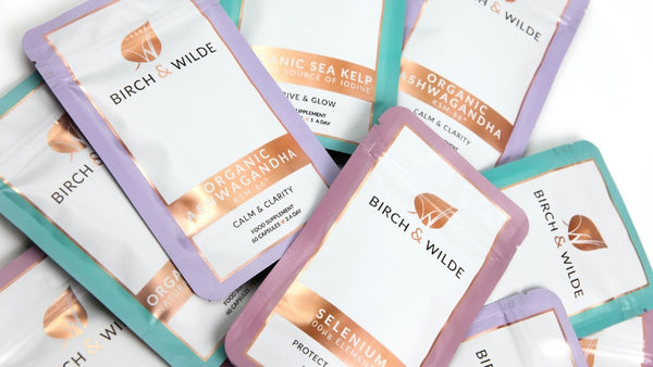Flat lay image of a selection of colourful supplement capsule refill packs from birch and wilde including organic ashwagandha, elemental selenium and organic sea kelp (iodine)