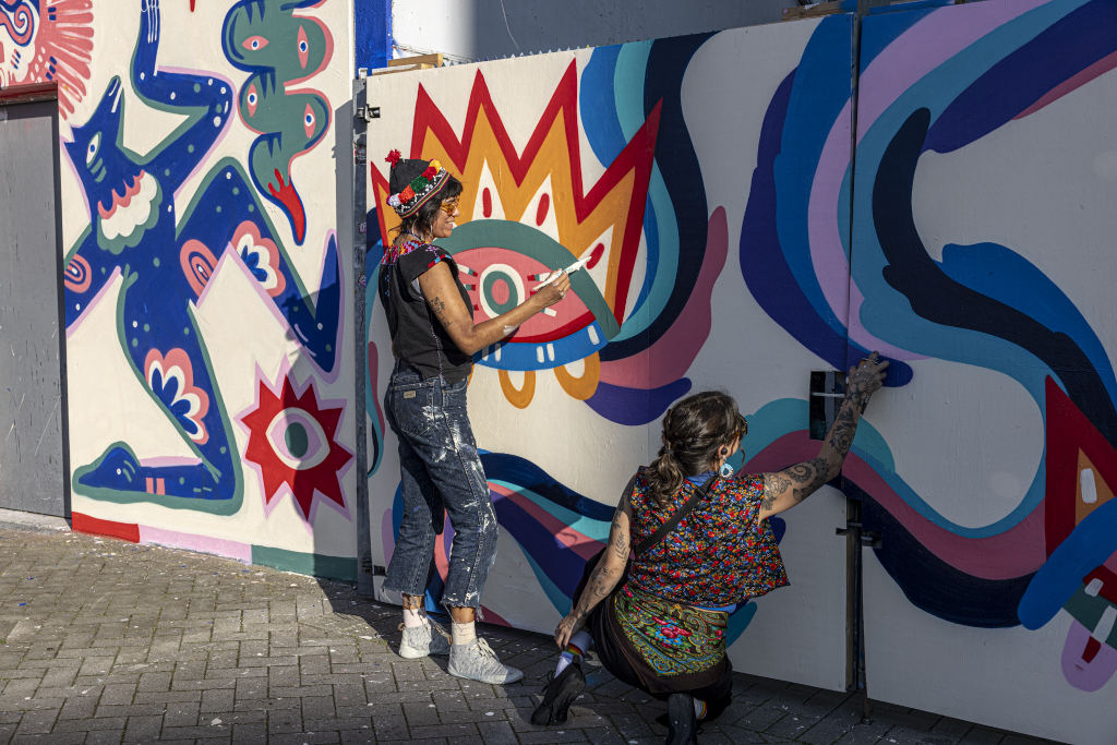 The artists Jumu Monster and Mari Pavanelli painting a mural in Hamburg.