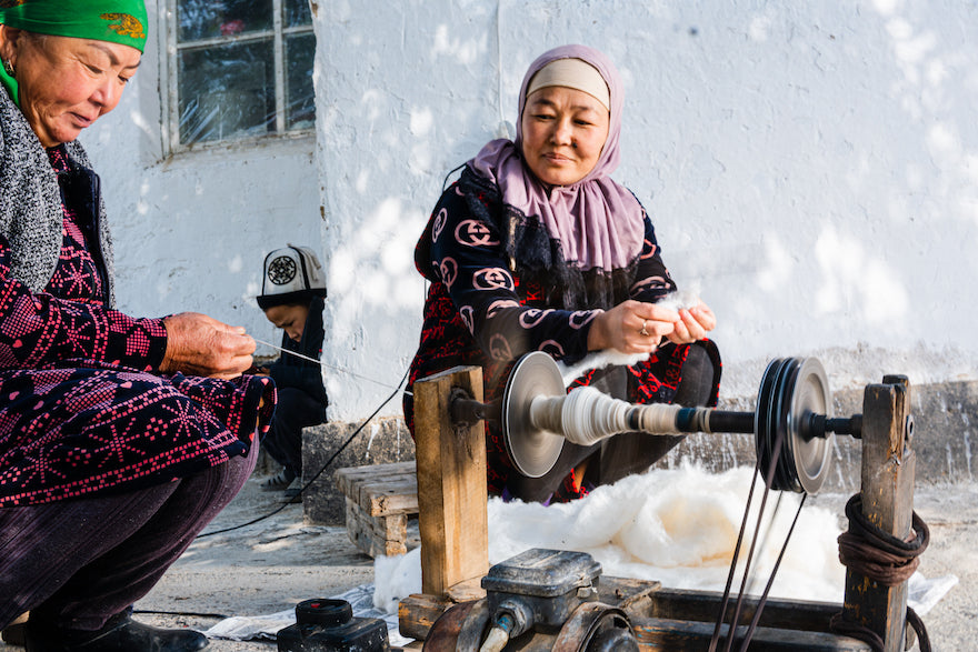 Zwei Frauen aus Kirgistan verspinnen Baumwolle mit der Hand.