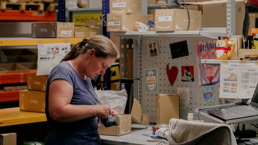 A person checks a shoe. The Wildling warehouse is in the background.