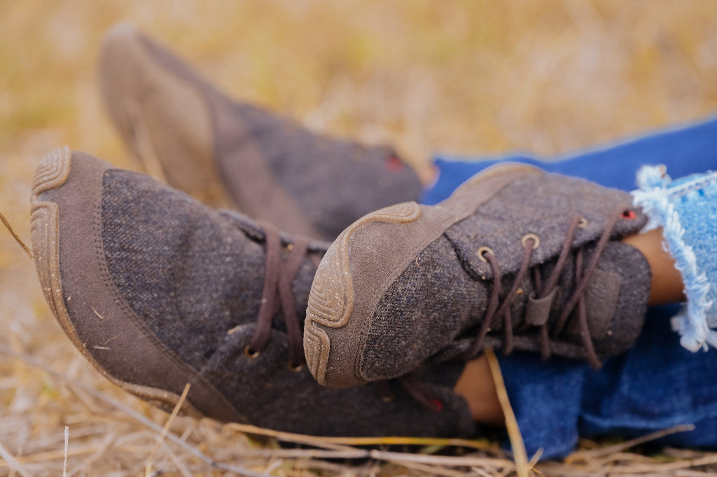 Nahaufnahme: Ein Paar erwachsene und ein paar Kinderfüße, beide in Wildling Barfußschuhen.