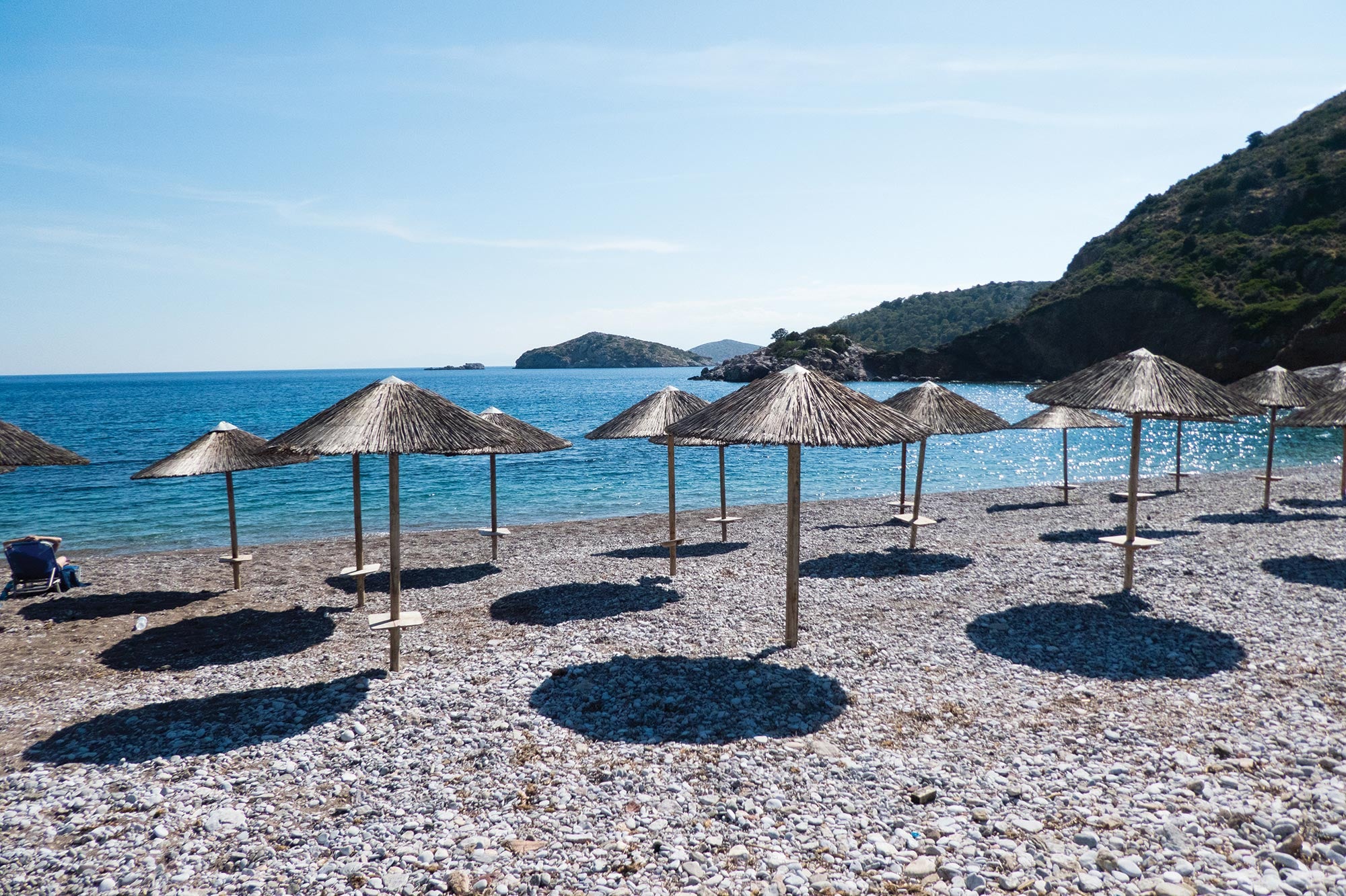 thatched umbrellas on a beautiful beach in Hydra, Greece