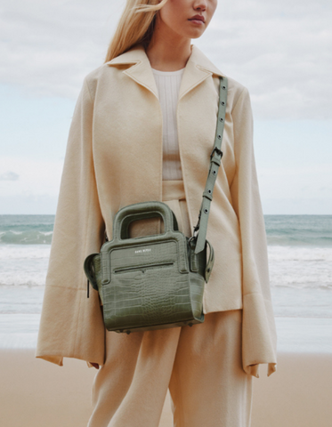 Cropped image of Dechen wearing a cream knit suit with a pale green Sans Beast handbag worn crossbody.
