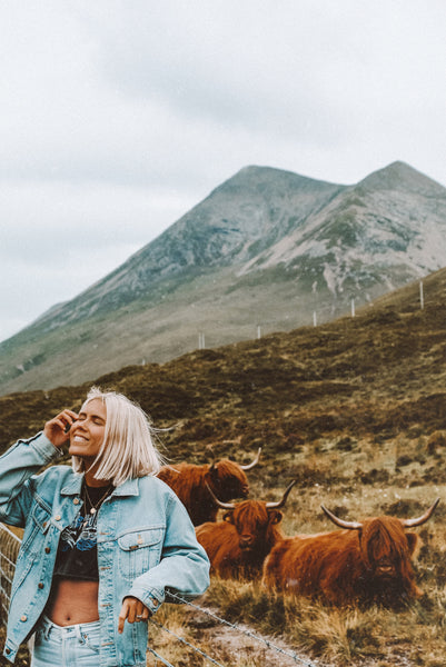 Karissa in the Scottish Highlands, standing near a group of cows