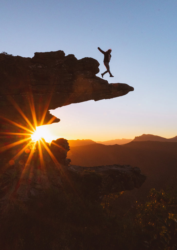 Sarah Byden jumping above a clifftop during a stunning sunset