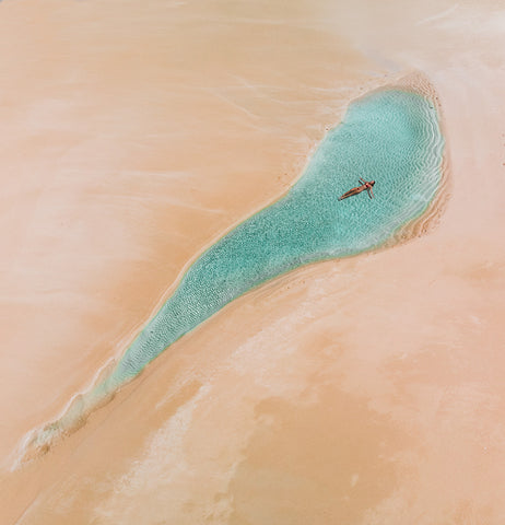 Sarah Byden floats in clear water on a beach