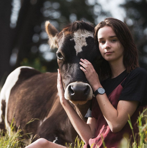An image of Emma Hakansson snuggled next to a beautiful cow and touching it's face.