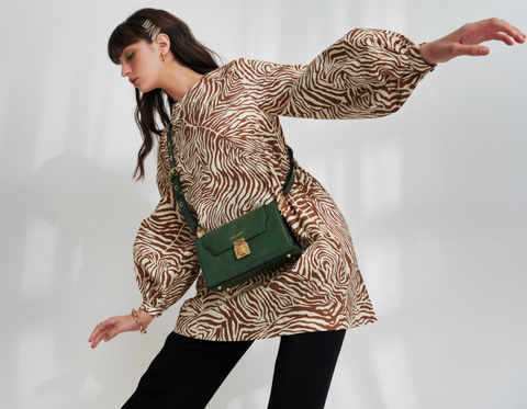 Paris wears a brown zebra print blouse with a green Sans Beast vegan handbag worn crossbody