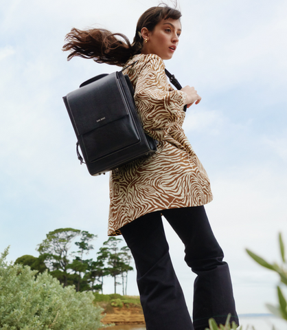 Paris wears a brown + cream zebra print top with a black Sans Beast vegan backpack on her back