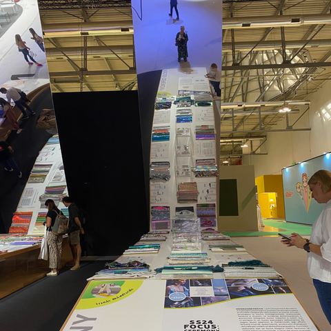 Image of trend area at Micam trade fair showing a long bench with multiple swatches in various colours on it, a large mirrored wall stands at the back