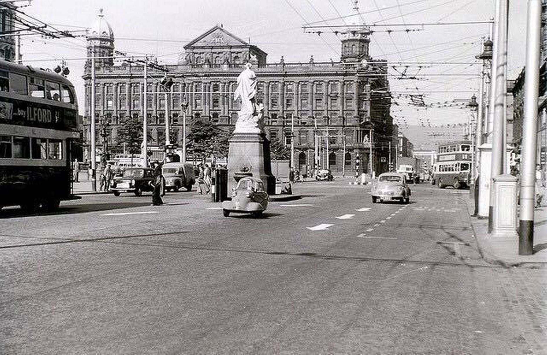 The image from 1950s shows the Titanic memorial in front of the city hall, the trams and pedestrians have disappeared and cars and buses are now becoming more popular.