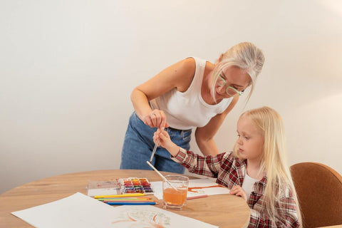 woman in her 50s teaching a young girl to watercolor