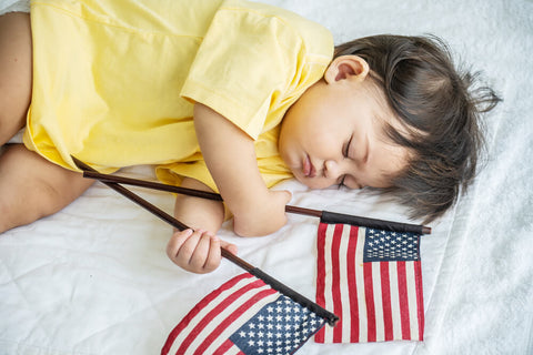 Cute baby sleeping with American flags 4th of July parade