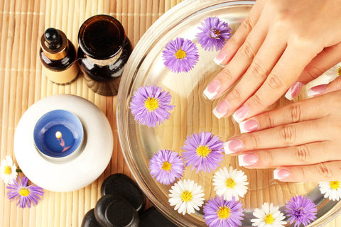 manicured hands over a water soak with flowers