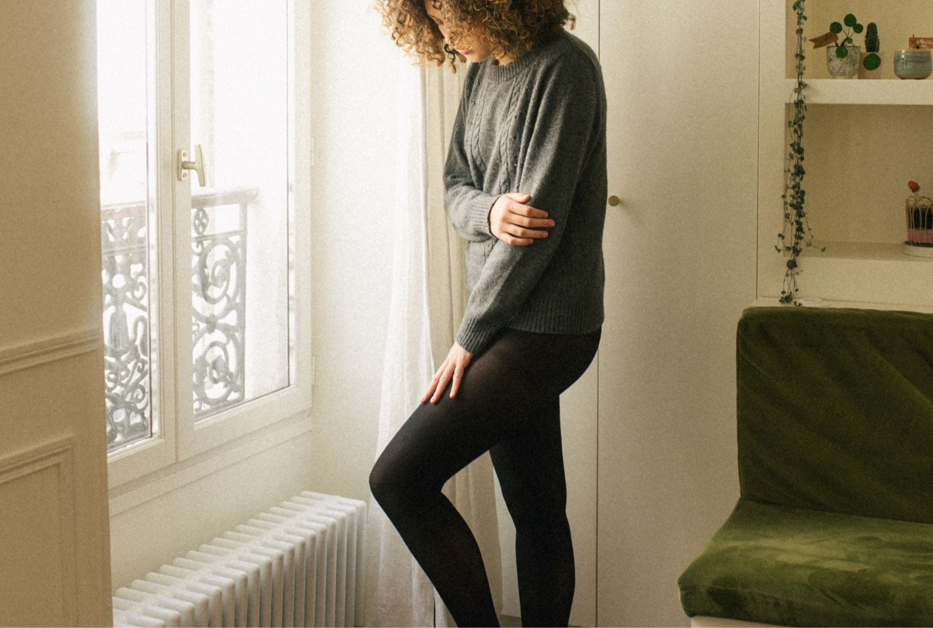 Atelier Unes - Entretien collants - Femme portant une paire de collants noirs recyclés 40 deniers et un pull en laine mérinos recyclée fabriqués en Europe par Atelier Unes