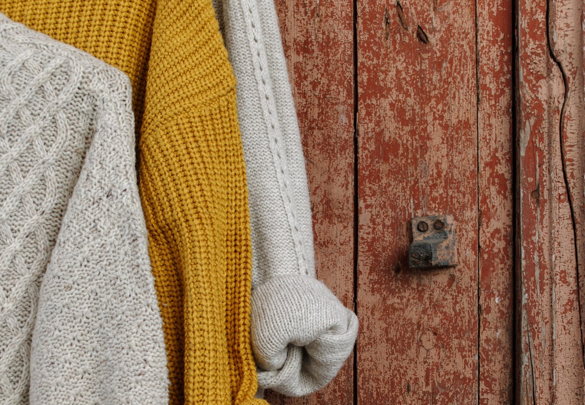 Atelier Unes - Entretien laine - Zoom sur des vêtements en laine attachés à une porte