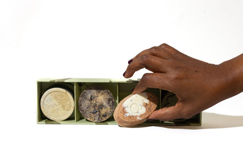 A hand reach for a mini soap in a green gift box