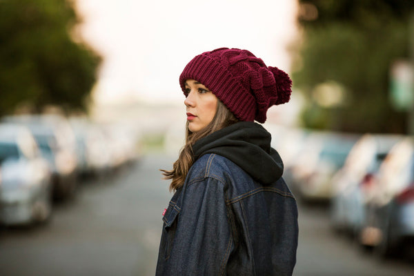 Northstar cable knit, extra long, blank pom beanie in burgundy on a girl in a denim jacket.  Photographed on location San Francisco, Marina district.  By Blvnk Headwear.