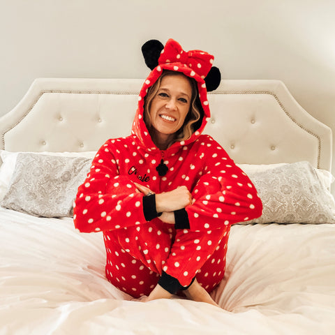 Woman on bed wearing red polka dot minnie mouse onesie