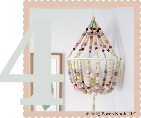 Large Handcrafted Wool Felt Chandelier with Tassel. Make your space even sweeter with this adorable, handcrafted wool felt chandelier shaped mobile! Playfully sophisticated, hand felt pom poms are elegantly strung with white twine ending with a soft yarn tassel.
