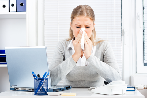 woman at desk sneezing