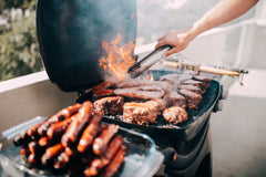 Close up on man grilling lots of meat with a flame