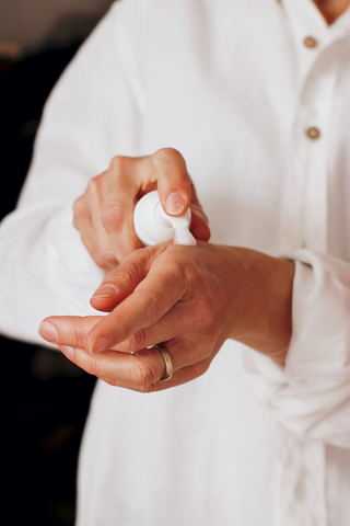 A person using hand lotion or cream on their wrist.