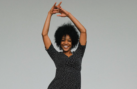 Black woman with textured type 4 natural hair dancing and smiling