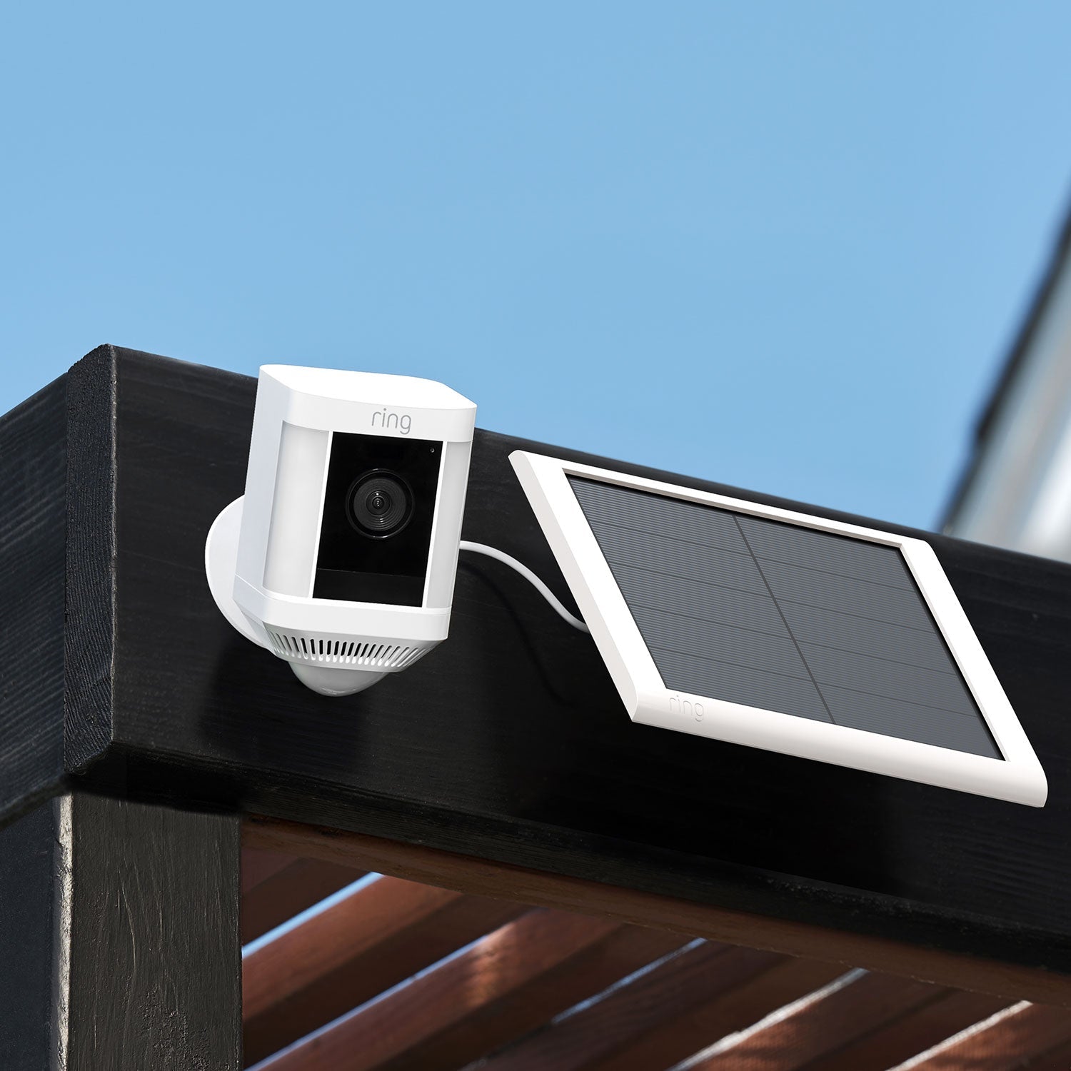 Spotlight Cam Plus (Solar) - Spotlight Cam Plus and Solar Panel, both in white, mounted on the corner of a pergola.