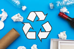 recycle symbol with paper, plastic, and cardboard items