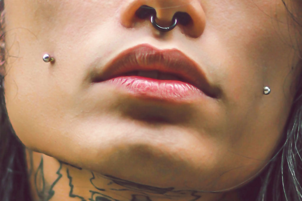 Hombre con piercings en la mejilla/dimple