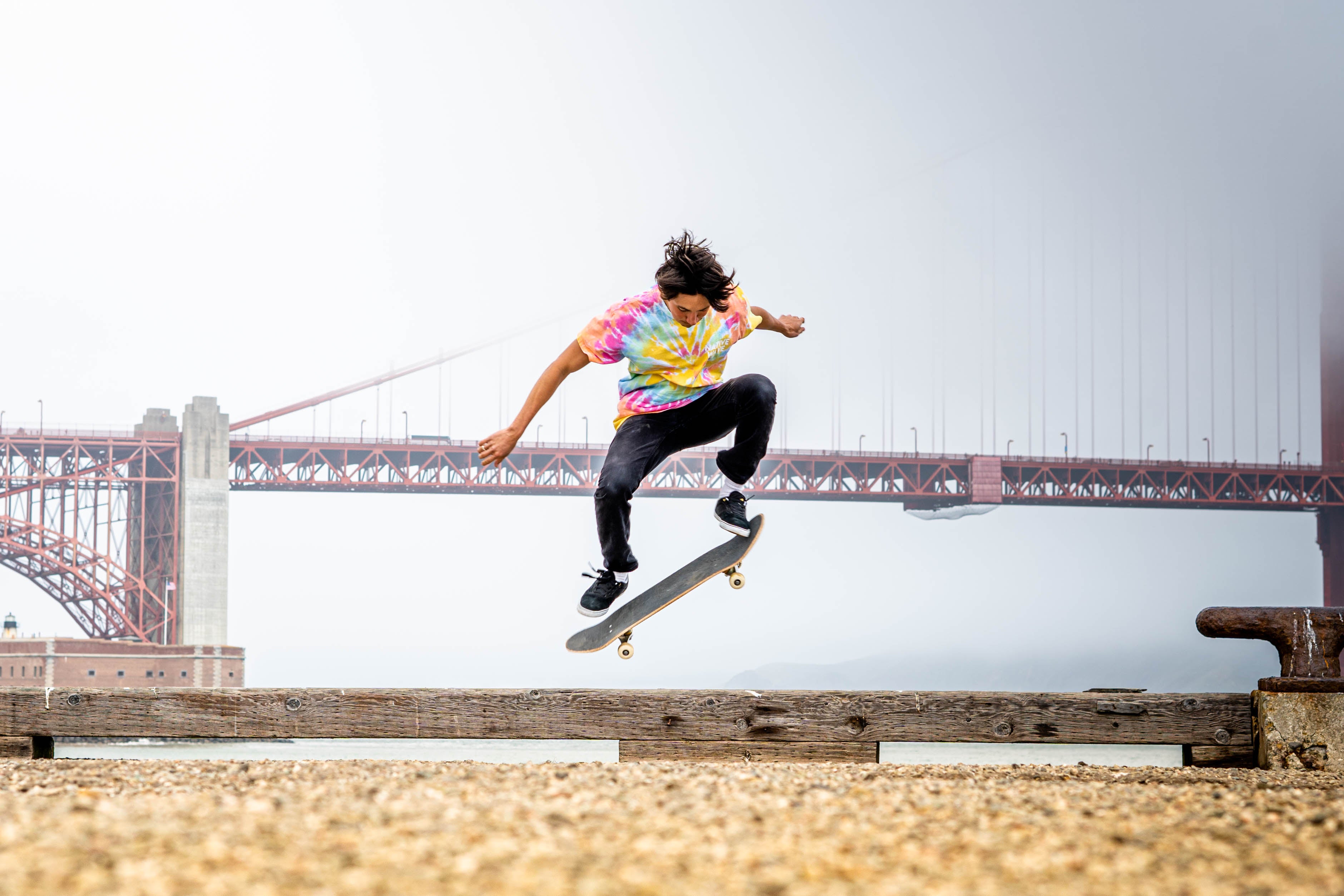 man skateboarding on pathway viewing bridge