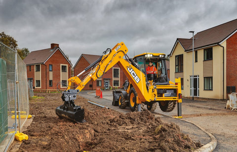 3CX Backhoe Loader using the backhoe arm to grade top soil in a new build development