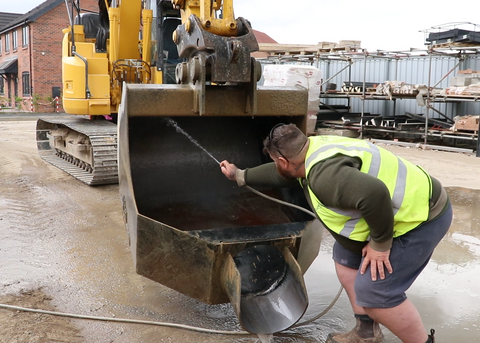 Rhinox concrete pouring bucket being cleaned with a hose
