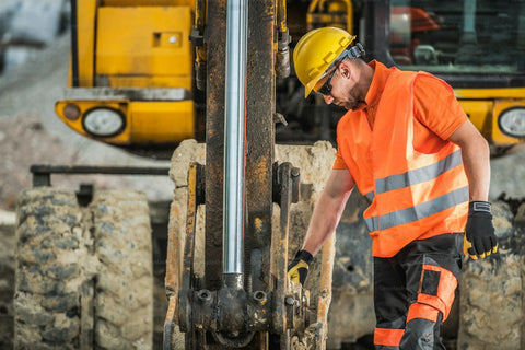 Excavator operator inspecting the machine before use, wearing PPE (Hard hat, glasses, gloves, hi-vis clothing)