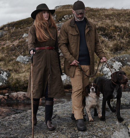 A lady wearing the Hoggs Of Fife Ladies Struther long length riding coat alongside a man and two dogs