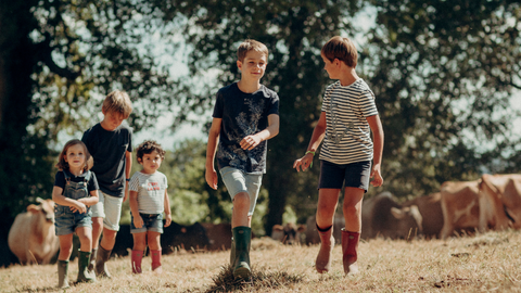 Five children wearing Wellington boots walking through a field