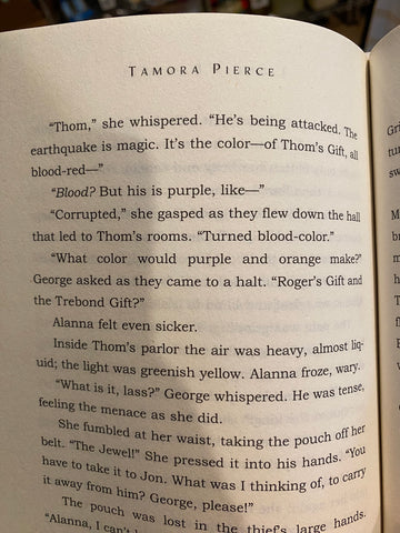 An excerpt from Alanna's First Adventure that reads "Thom," she whispered. "He's being attacked. The earthquake is magic. It's the color - of Thom's Gift, all blood-red-" "Blood? But his is purple, like-" "Corrupted," she gasped as they flew down the hall that led to Thom's rooms. "Turned blood-color." "What color would purple and orange make?" George asked as they came to a halt. "Roger's Gift and the Trebond Gift?" Alanna felt even sicker.