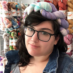 A photo of a young woman in her mid-twenties with a crown of yarn