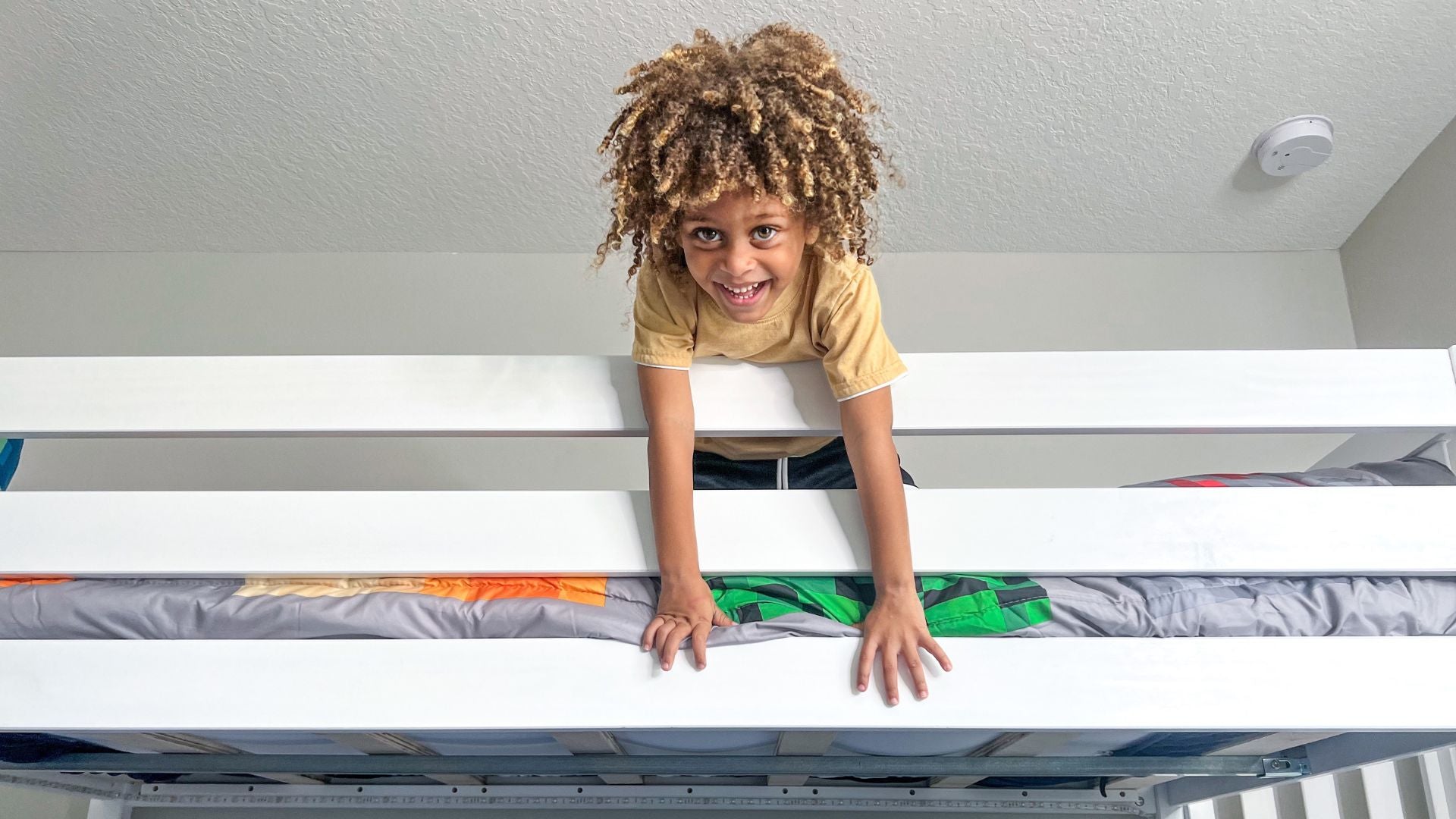 Boy looking over guard rail of white solid wood bunk bed