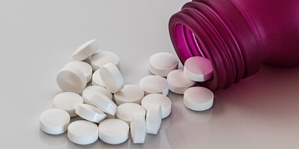 A pink cold sore prescription medicine bottle poured out on a table. 