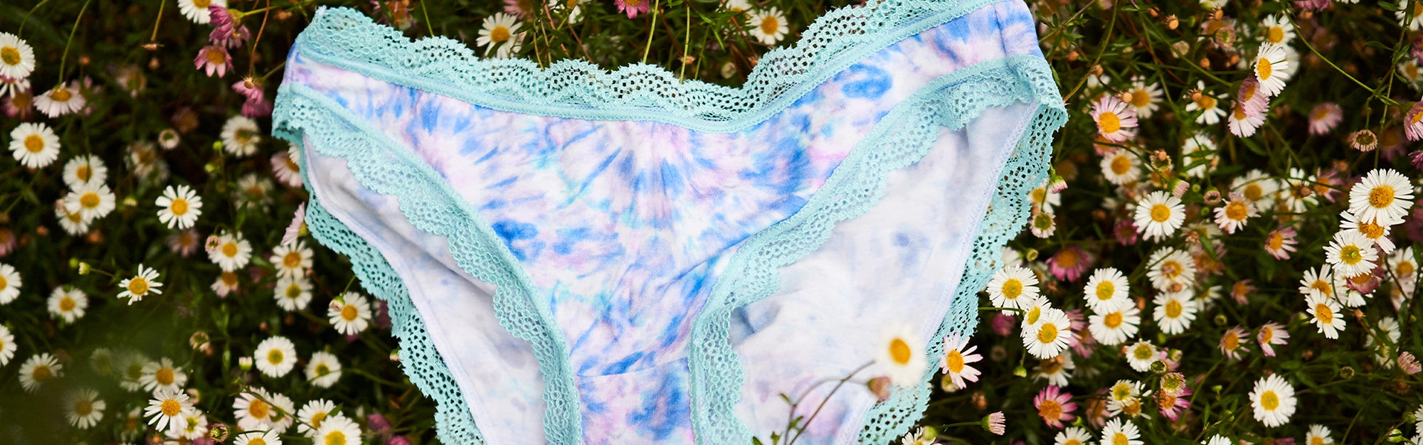 Tie dye print knickers on grass surrounded by daisies