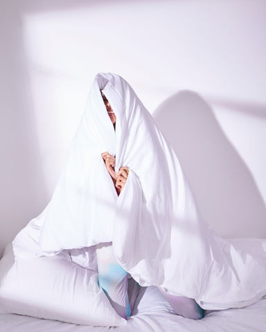 Woman hiding underneath a duvet